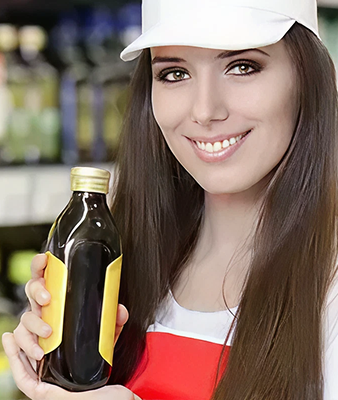 Smiling woman in a cap holding a beverage bottle, representing in-store product demonstrations for beer coaster advertising campaigns.