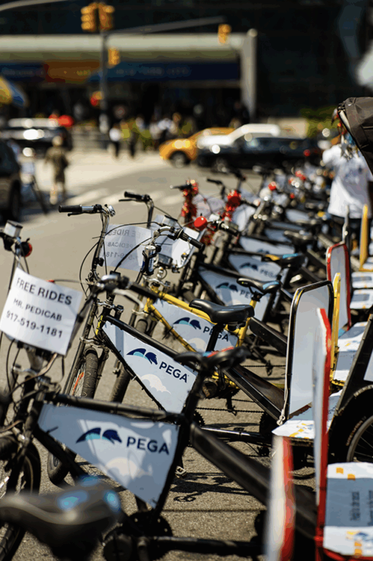 Bicycles lined up for free rides, featuring promotional signage for PEGA, showcasing experiential marketing in urban settings.