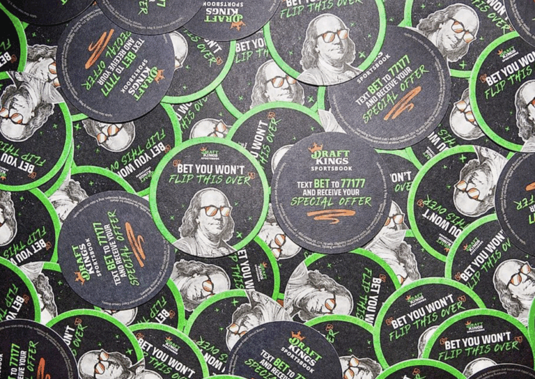 DraftKings promotional coasters featuring the phrase "BET YOU WON'T FLIP THIS OVER," surrounded by images of Benjamin Franklin, emphasizing immersive brand engagement and experiential marketing strategies.