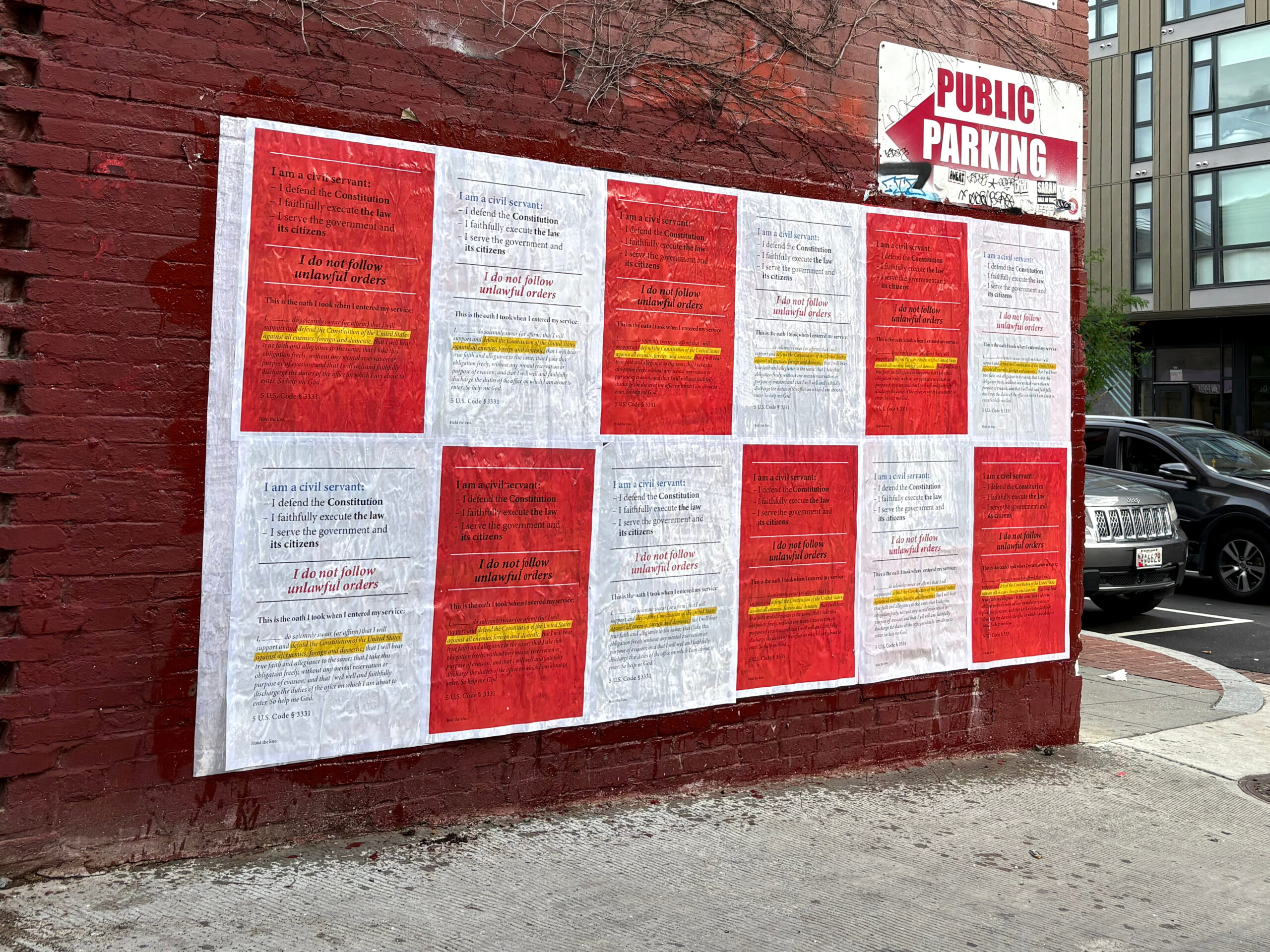 Posters on a brick wall featuring emotional storytelling messages in red and white, promoting nonprofit awareness and community engagement, with a "Public Parking" sign visible above.
