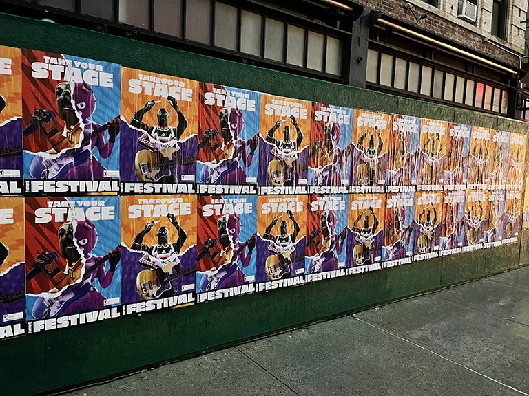 Wild posting campaign featuring multiple colorful posters for Fortnite's "Take Your Stage" festival, displayed on a green wall in an urban setting.
