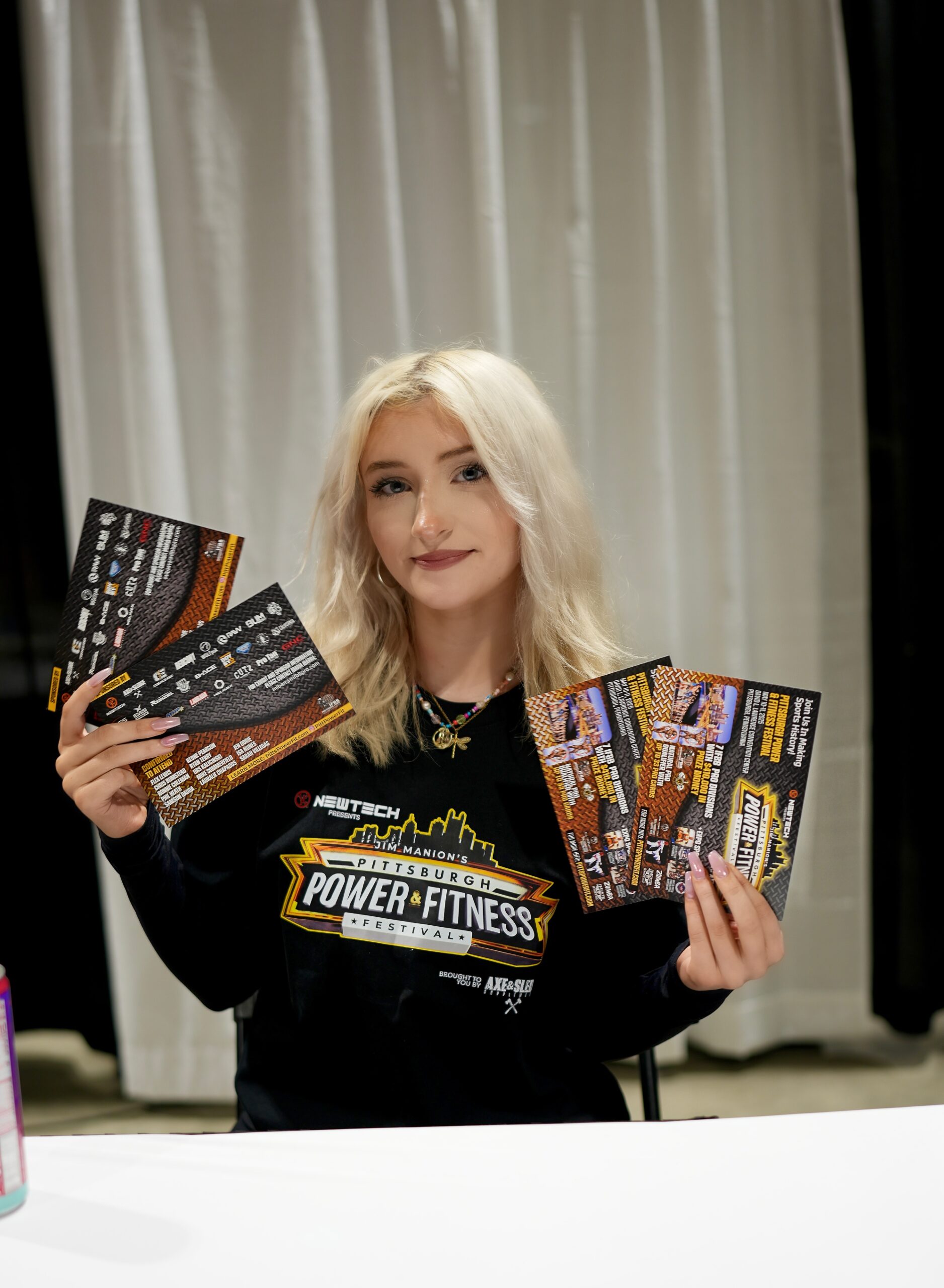Brand ambassador at the Pittsburgh Power & Fitness Festival holding promotional materials, showcasing brand engagement and marketing efforts.