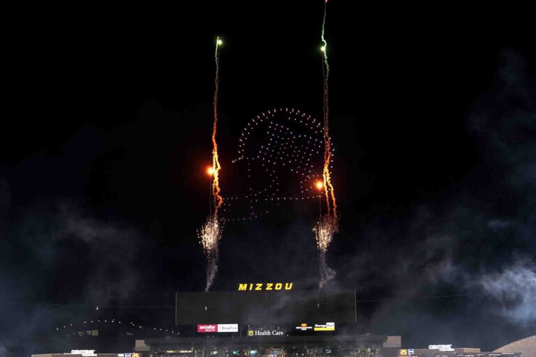 Fireworks and drone formations creating the Mizzou logo during the halftime show at the Columbia stadium, showcasing a vibrant display of light and pyrotechnics.