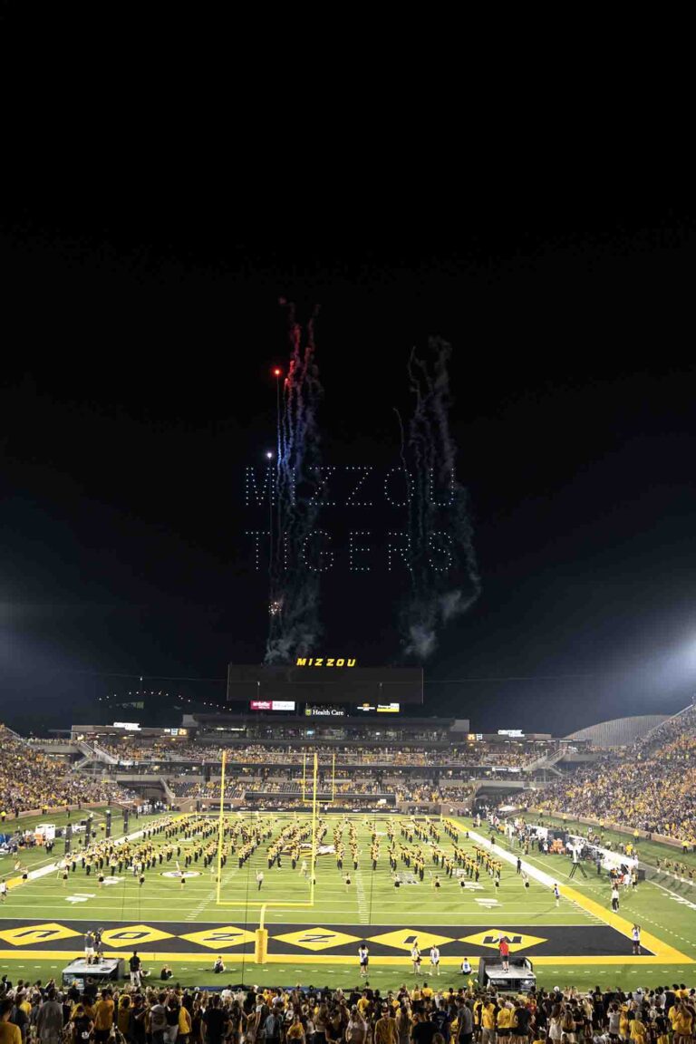 Drone light show displaying "MIZZOU TIGERS" above a packed stadium during the halftime show, with fireworks enhancing the performance and Marching Mizzou in formation on the field.