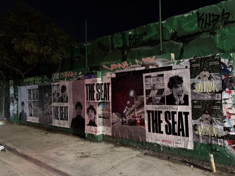 Wheatpasted posters featuring "The Seat" campaign by Netflix, displayed on a construction wall in Miami, showcasing multiple images and text, strategically placed for high visibility during F1 weekend.