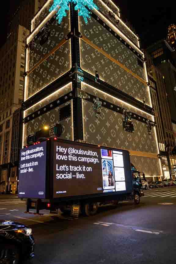 LED billboard truck displaying a social media campaign for Louis Vuitton in Manhattan, New York, illuminated at night with a prominent digital screen showcasing engaging messages.