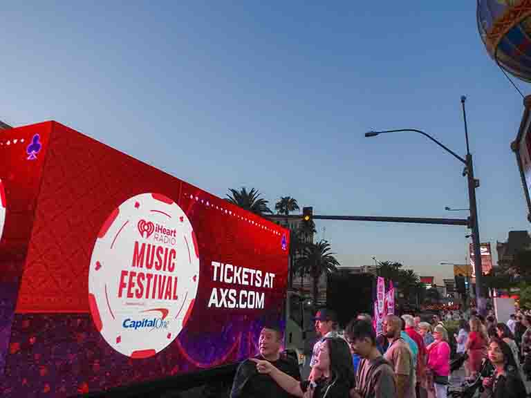 iHeartRadio Music Festival LED billboard truck activation displaying vibrant advertisement with crowd in Manhattan, New York, promoting ticket sales at AXS.com.
