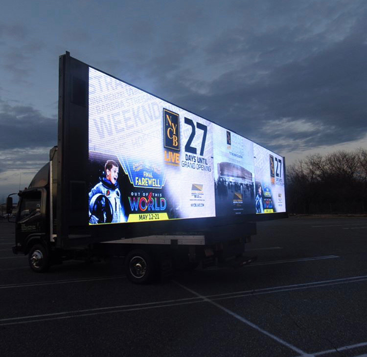 14ft LED billboard truck displaying countdown to NYCB Live grand opening, featuring promotional graphics and event details, set against a cloudy sky.