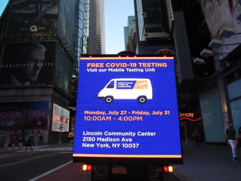 LED billboard truck displaying information about free COVID-19 testing, including testing dates and location at Lincoln Community Center, Times Square, New York.