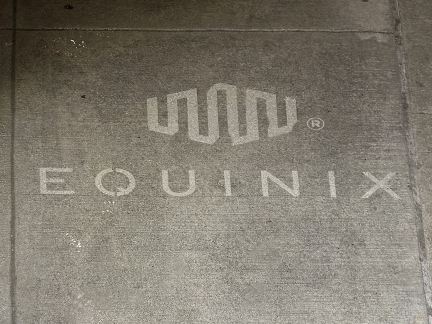 Equinix logo and branding displayed on sidewalk stencil, promoting outdoor advertising effectiveness for urban marketing.