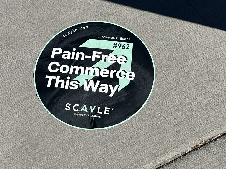 Sidewalk decal featuring "Pain-Free Commerce This Way" and SCAYLE branding, promoting a Shoptalk booth.