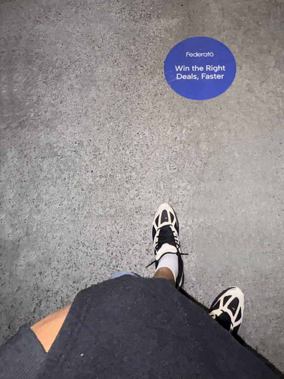 Federato sidewalk decal with the phrase "Win the Right Deals, Faster," featuring a person's feet wearing sneakers above the decal.