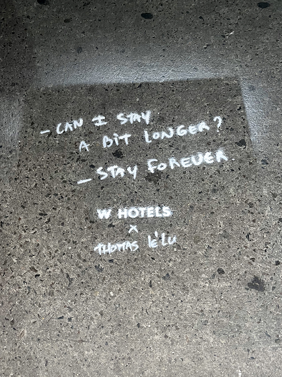 Sidewalk stencil art featuring text "Can I stay a bit longer? Stay forever" with W Hotels and Thomas Le'l branding, promoting urban artistry and guerrilla marketing techniques.