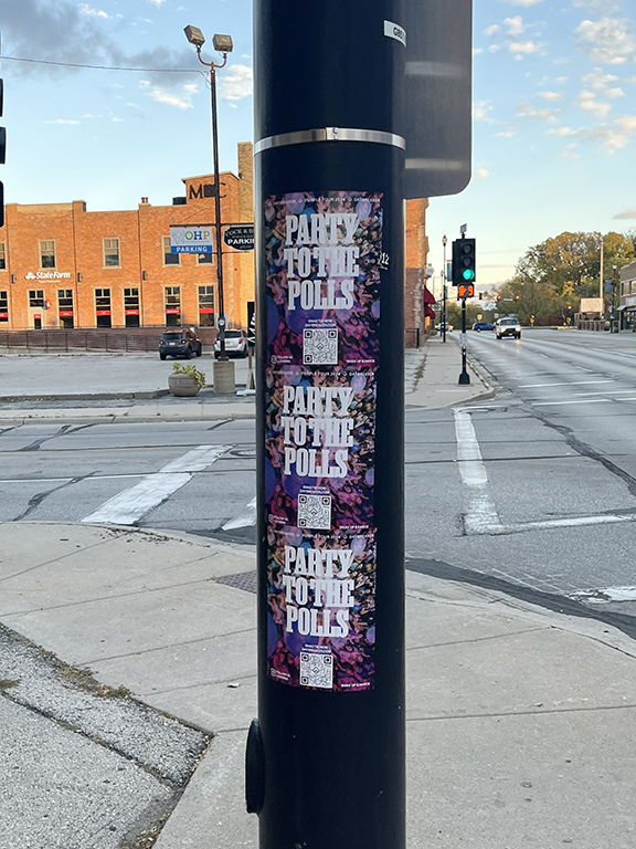 Posters for "Party to the Polls" DJ campaign on a street pole in Los Angeles, featuring vibrant graphics and QR codes for event engagement.