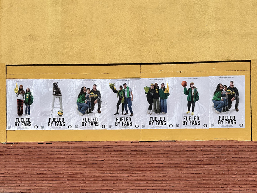 Wheatpaste posters featuring diverse groups of fans in green apparel, showcasing the University of Oregon's "Fueled By Fans" campaign, displayed on a yellow wall.