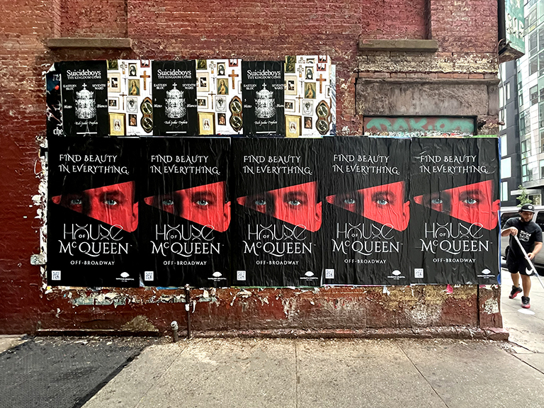 Wheatpaste poster advertisement for "House of McQueen" Off-Broadway campaign featuring striking red imagery and the tagline "Find Beauty in Everything," displayed on a brick wall in an urban setting.