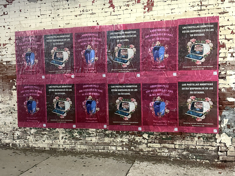 Wheatpaste posters promoting abortion pills availability in all 50 states, featuring vibrant designs and bilingual text, displayed on a brick wall in an urban setting.
