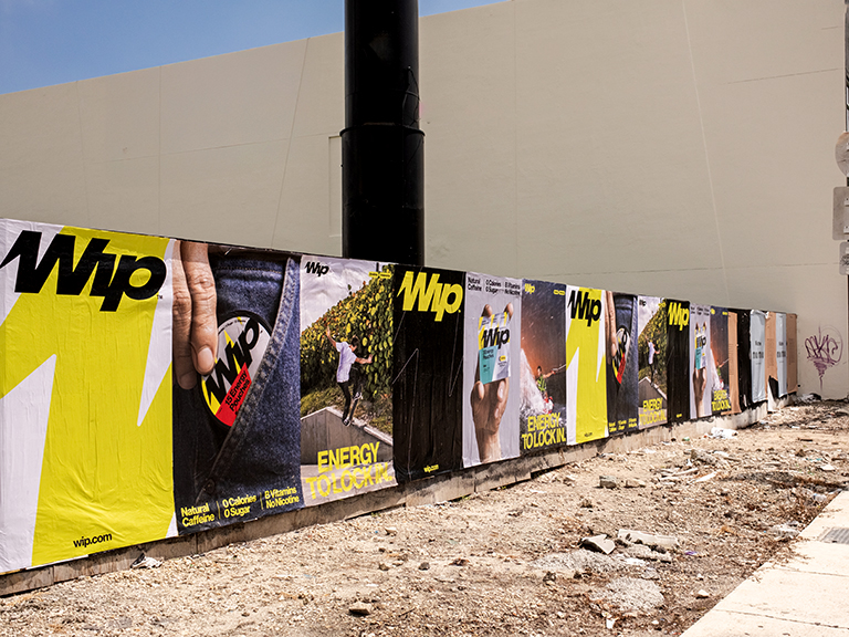 WIP wheatpaste advertising campaign featuring vibrant posters with dynamic visuals and bold text in an urban setting, showcasing energy and lifestyle themes.