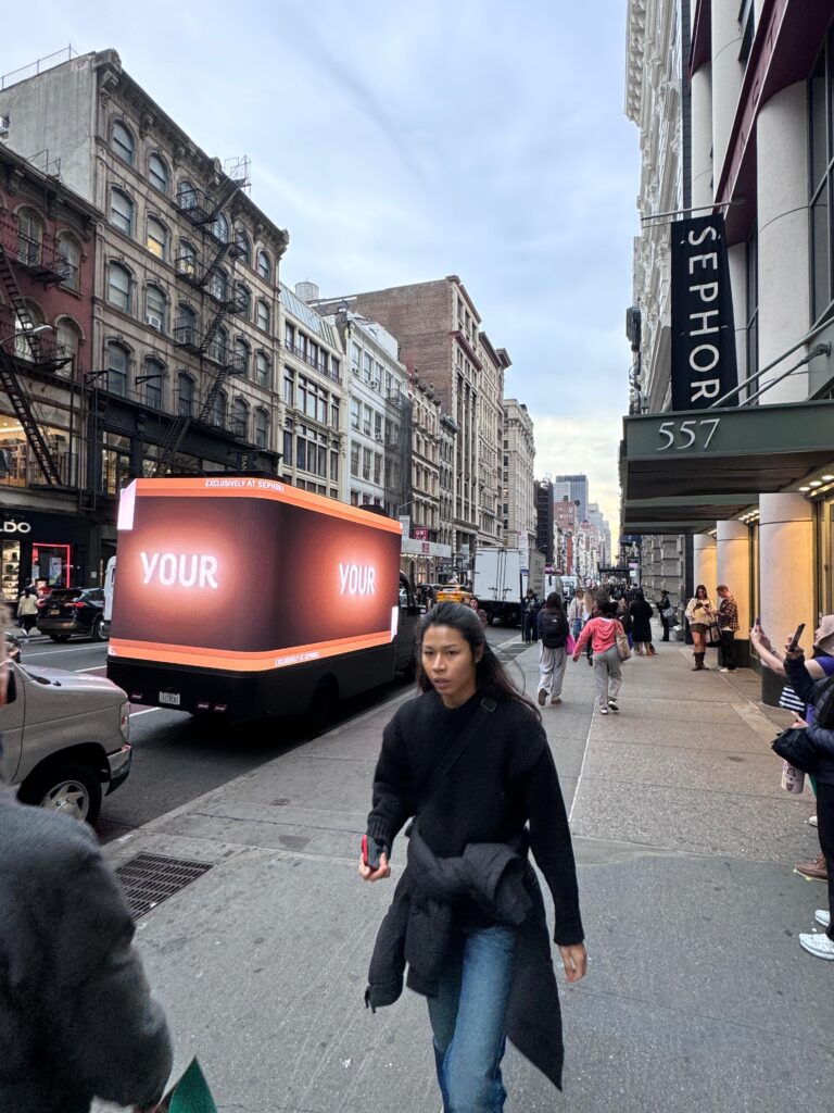 3D LED billboard truck promoting Biossance skincare products on a busy New York City street near Sephora, with pedestrians engaging in the vibrant marketing activation.