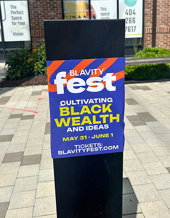 Blavity Fest promotional poster on a pole, featuring vibrant colors and text highlighting the event's focus on cultivating Black wealth and ideas, scheduled for May 31 to June 1.