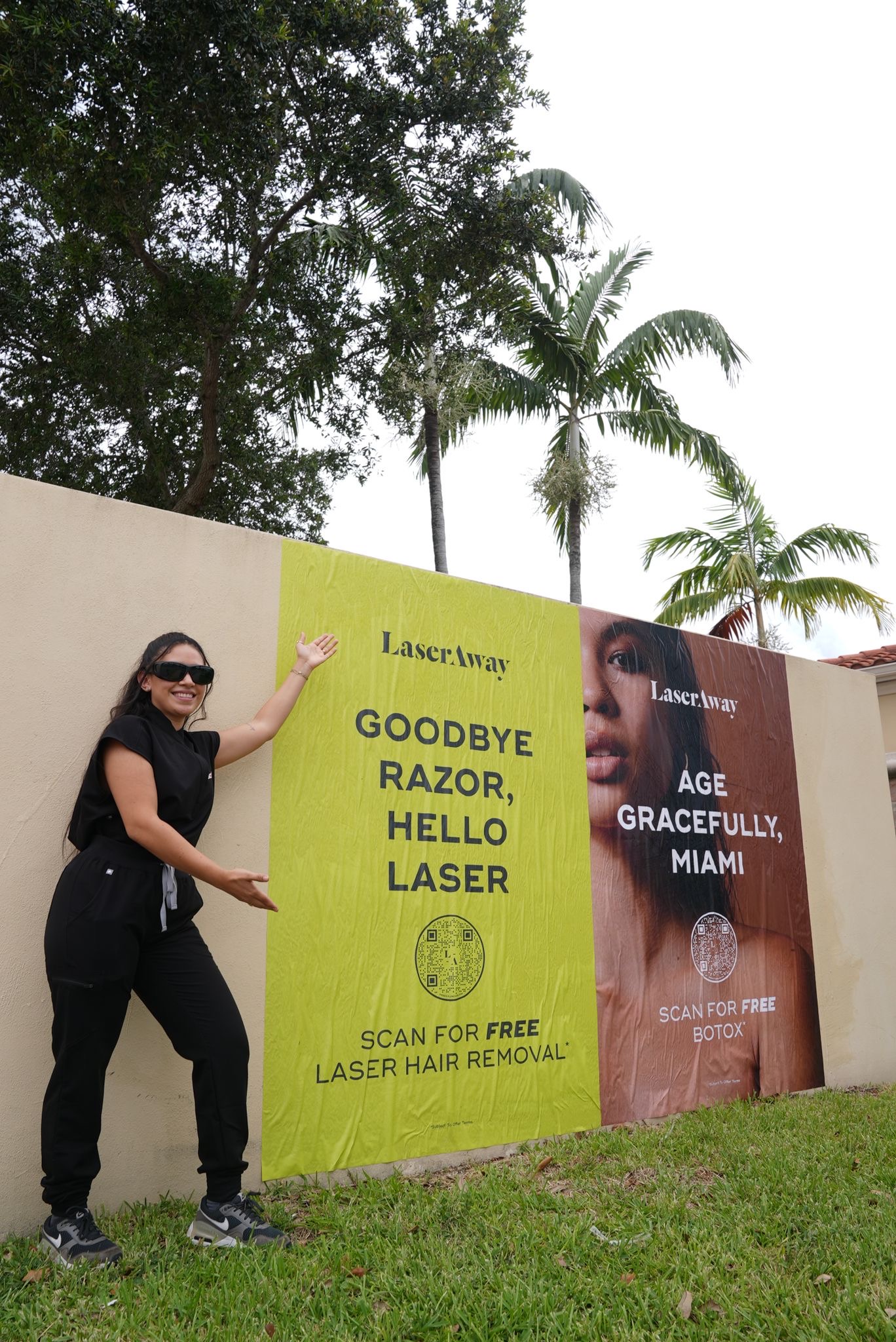 Woman promoting LaserAway billboard featuring laser hair removal and Botox services in a vibrant outdoor setting.