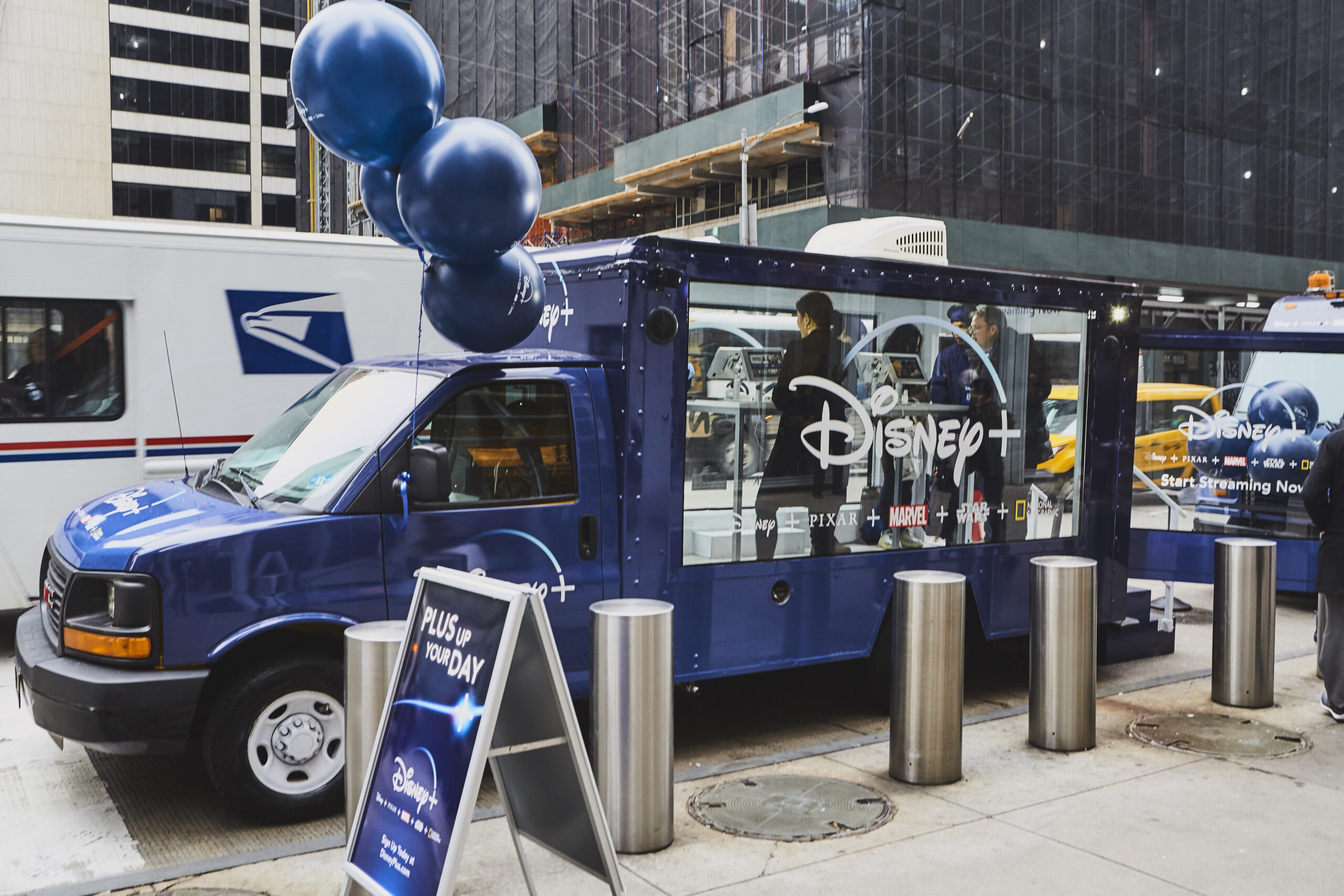 Mobile showroom truck featuring Disney+ branding, equipped with promotional balloons and signage, showcasing a dynamic advertising presence in an urban environment.