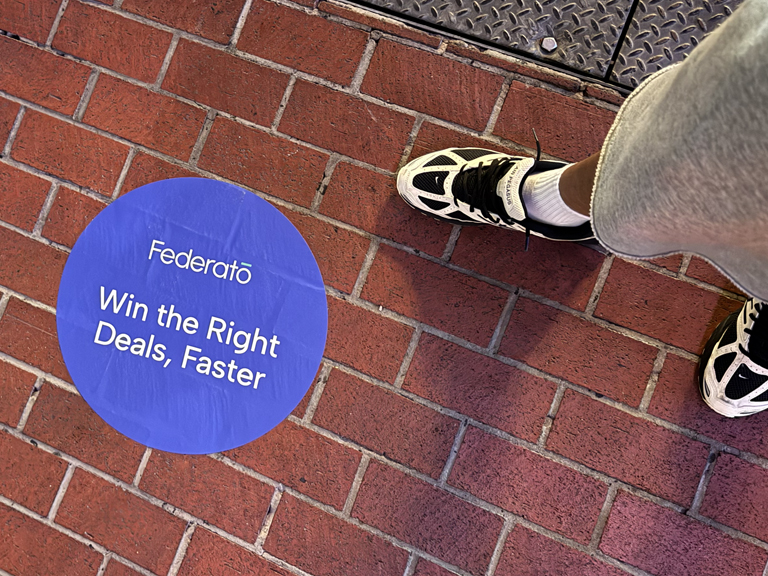 Footsteps on brick pavement near a circular blue floor graphic with the text "Federato Win the Right Deals, Faster," emphasizing street-level advertising and engagement at conventions.