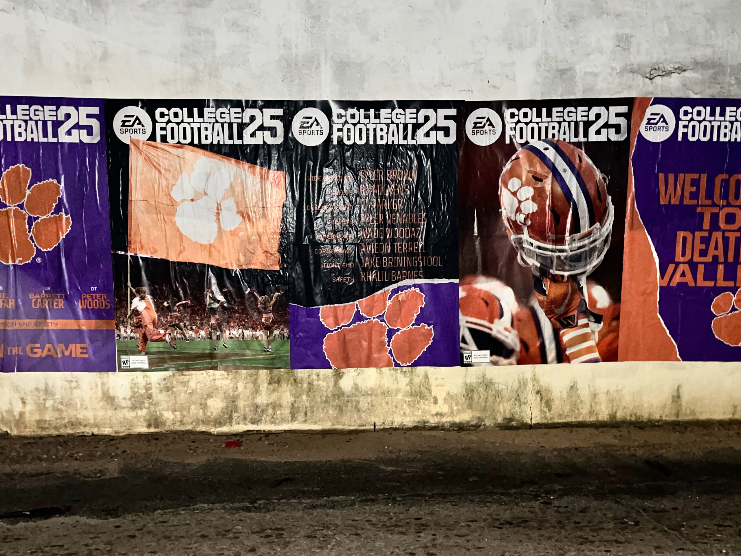 EA Sports College Football 25 wheatpasting campaign featuring bold posters with Clemson University imagery, including a paw print, player graphics, and promotional text, creating a vibrant street presence.