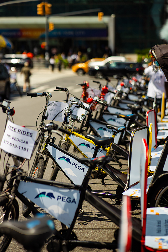 Pedicabs lined up on a busy NYC street, featuring promotional signs for free rides and branding for pedicab services, showcasing dynamic outdoor advertising opportunities.