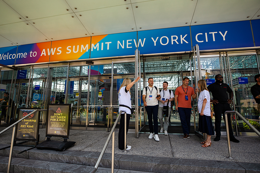 Welcome sign for AWS Summit New York City, attendees entering the venue, event atmosphere, professional networking.