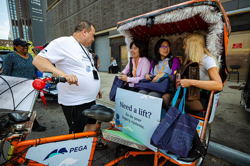 Pedicab advertising experience with driver and passengers engaging, featuring a promotional sign reading "Need a lift? So do your logo systems," in an urban setting.