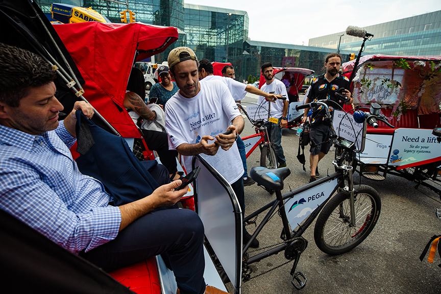 Pedicab drivers interacting with passengers in urban setting, showcasing pedicab advertising for Pega, emphasizing mobile marketing and customer engagement.