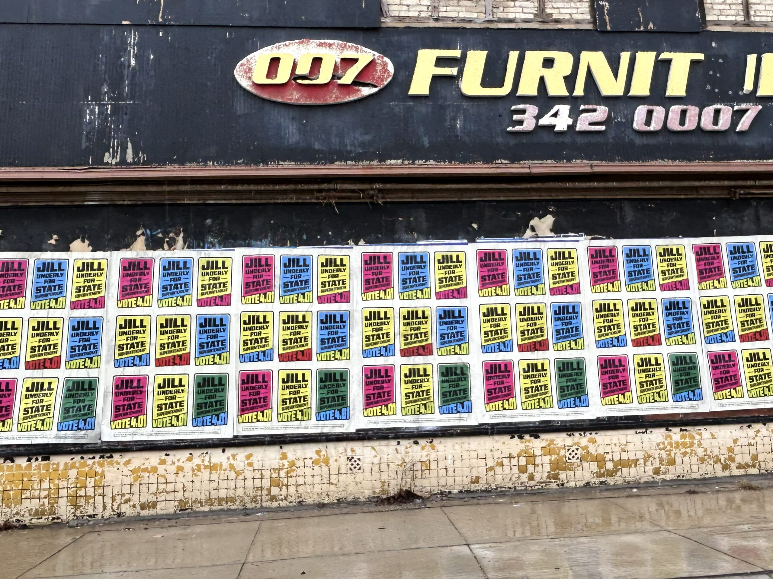 Jill Underly campaign posters in vibrant colors covering a brick wall, promoting her run for State Superintendent ahead of the April 1st election, emphasizing high-impact visibility and voter engagement strategies.