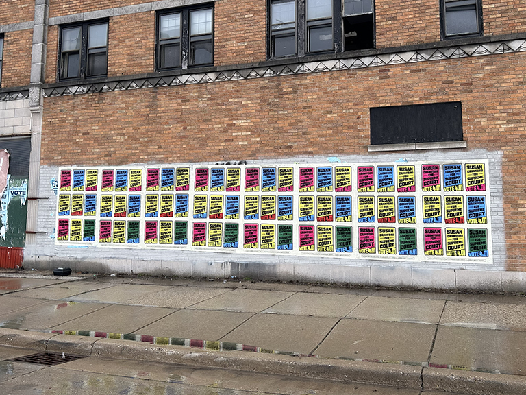 Vibrant wild posting wall featuring multiple campaign posters for Susan, utilizing bright colors and repeated messaging to enhance voter awareness in a high-traffic urban area.
