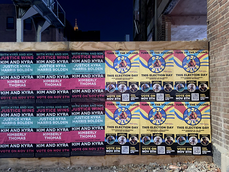 Nighttime wild posting wall featuring vibrant Kim and Kyra election posters with "Turn Up the Volume" designs, promoting voter engagement for the November 5th election.