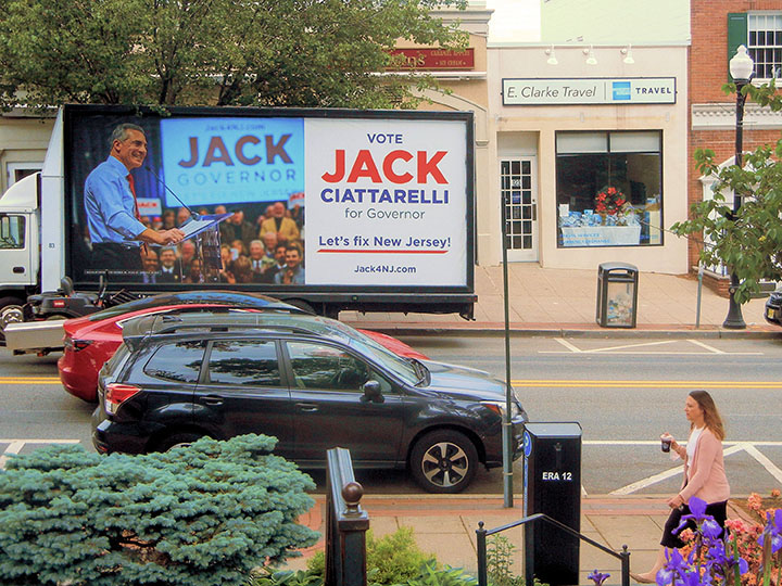 Jack Ciattarelli political billboard truck promoting his gubernatorial campaign with messaging aimed at New Jersey voters, positioned on a busy street with pedestrian traffic.