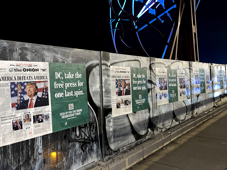 Nighttime wild posting activation featuring satirical newspaper-style designs from The Onion, promoting a humorous "Free Press" message with bold headlines and imagery, installed on a city wall to engage pedestrians and commuters.