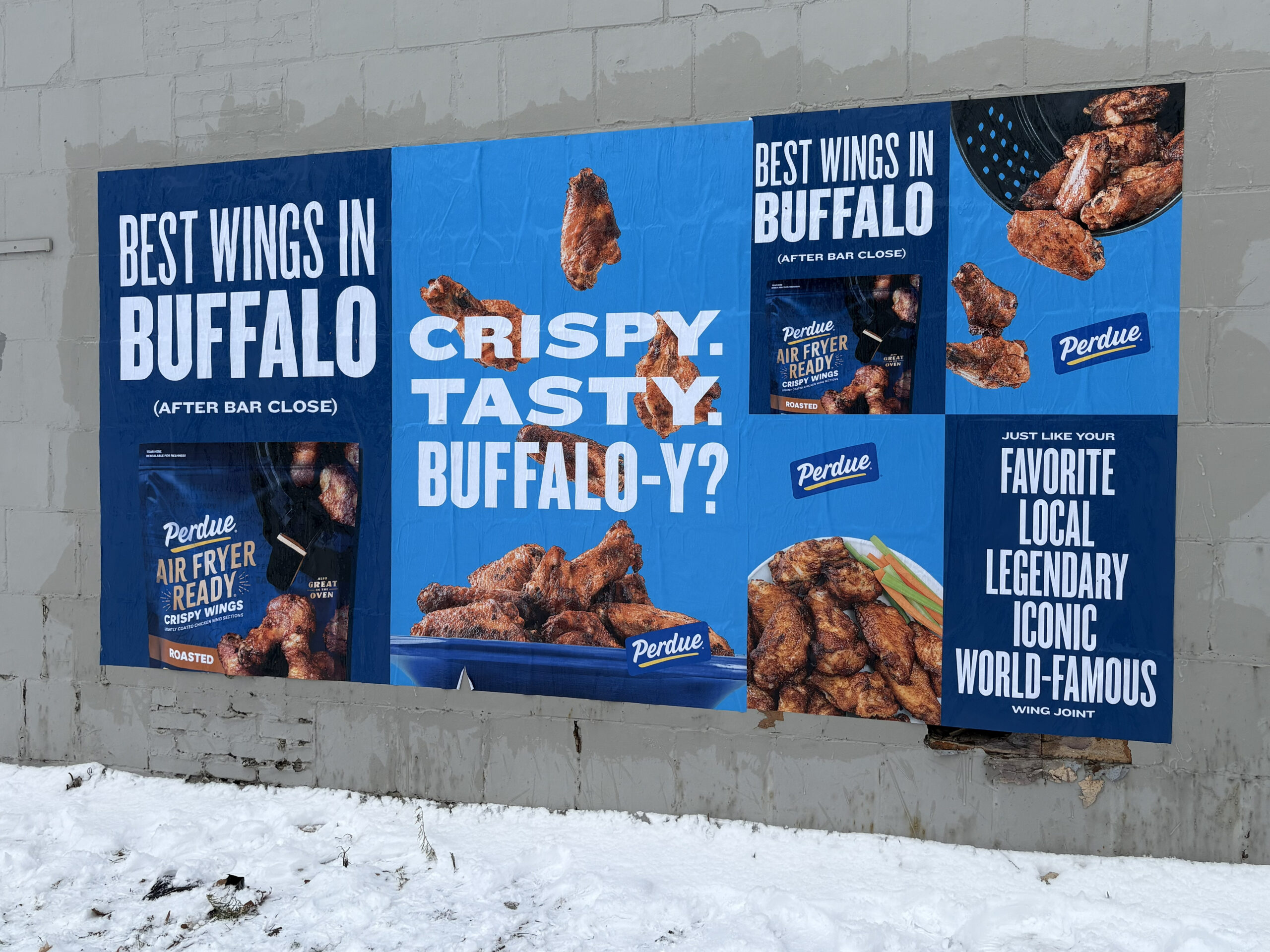 Billboard advertisement featuring Perdue's air fryer crispy wings, highlighting "Best Wings in Buffalo" with text emphasizing taste and local appeal, set against a snowy urban backdrop.