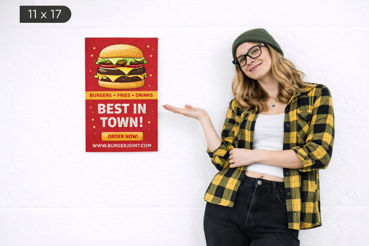 Woman in a plaid shirt gesturing towards an 11 x 17 inch poster featuring a burger advertisement with the text "BEST IN TOWN! ORDER NOW!" for a burger joint, emphasizing guerrilla marketing strategies.